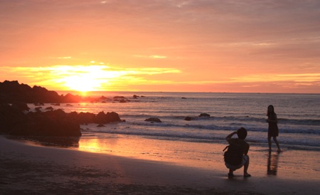 Đôi bạn trẻ thưởng thức bình minh trên một vùng biển.