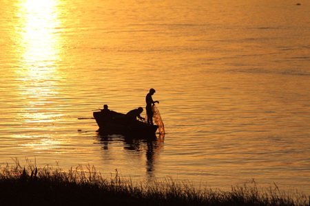 Ánh bình minh dọi chiếu cho ngư dân đánh cá.