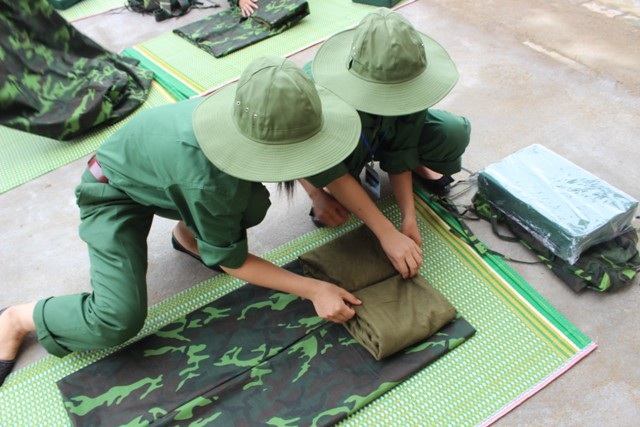 Các sinh viên trong lớp học quân đội thực hiện công việc kiên trì như xếp chăn màn...