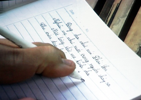 Thầy Tuấn hướng dẫn em Lê Thị Thắm cụt hai tay viết bằng chân.