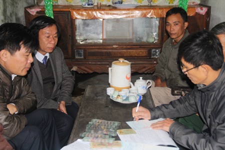 Ông Lê Đức Cường cùng cán bộ huyện và cán bộ ngân hàng làm thủ tục gửi tiền.