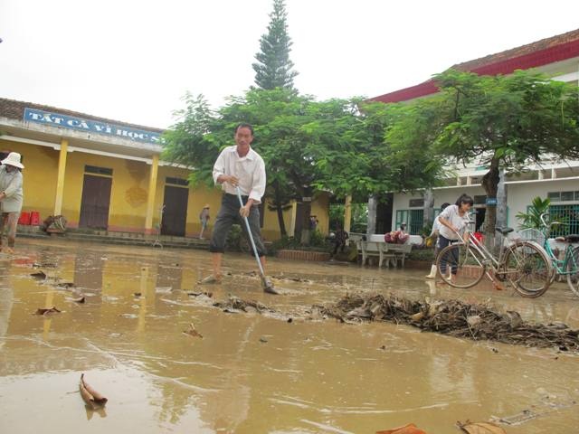 Thầy Văn Huy Tiến - hiệu trưởng trường tiểu học Quỳnh Dị cũng xắn quần lội bùn dọn dẹp.