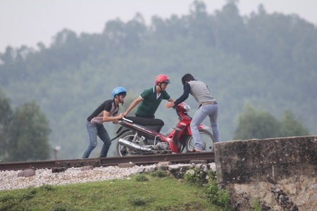 Nhiều thanh niên đã liều lĩnh dắt xe lên đường tàu đi để tránh đường ngập nước.
