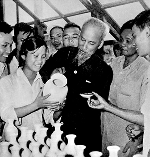 Bác viết chữ lên bình gốm trong một lần đến thăm nhà máy gốm.