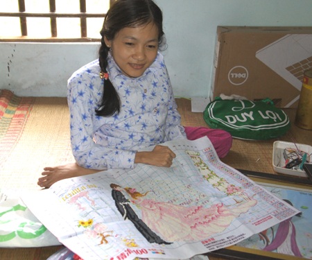 Nga bên bức tranh thêu dở của mình.