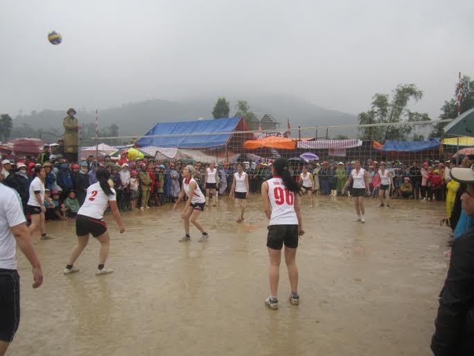 Các vận động viên nữ tham gia thi đấu bóng chuyền dưới trời mưa tầm tã.