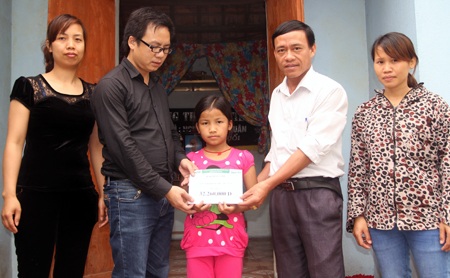 PV Dân trí cùng đại diện chính quyền xã Nghi Tiến trao quà đến bé Nhi.