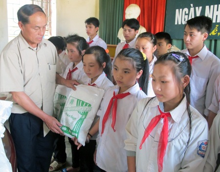 Ông Thò Chỏm Pó - Phó Chủ tịch UBND xã Tri Lễ trao những chiếc màn đến các em học sinh.