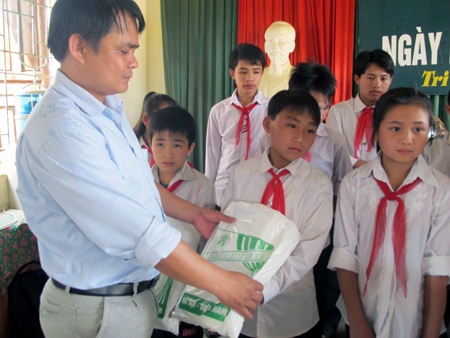 Ông Thò Chỏm Pó - Phó Chủ tịch UBND xã Tri Lễ trao những chiếc màn đến các em học sinh.