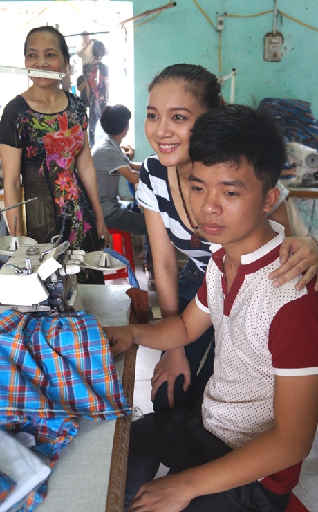 Cạnh chiếc máy khâu, Bích Trâm chụp ảnh với một người khuyết tật.