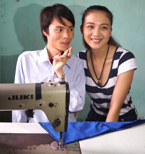 Cạnh chiếc máy khâu, Bích Trâm chụp ảnh với một người khuyết tật.