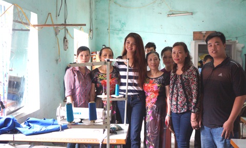 Cạnh chiếc máy khâu, Bích Trâm chụp ảnh với một người khuyết tật.