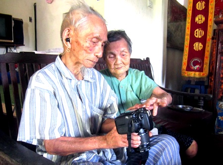 Hai cụ cùng nhau xem lại những bức hình của mình do PV chụp.