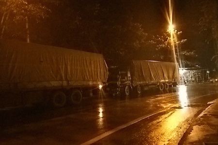 Xe chở gỗ mang biển số Lào "tung hoành" trên quốc lộ 7A - 5 Phía sau chiếc xe được khoanh tròn, còn 4-5 xe khác đỗ dọc hai bên đường cạnh một cây xăng.