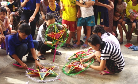 Các tình nguyện viên căng đèn ông sao, dán giấy... tổ chức cho các em.