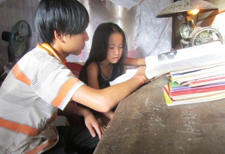 Người phụ nữ bệnh tật nuôi 2 cháu mồ côi - 1 Tranh thủ những lúc nghỉ làm thuê Thắng dạy em gái học bài.