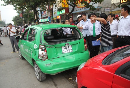 Hai chiếc xe (một taxi) và một chiếc xe của khách đang đứng gần đó bị vạ lây...