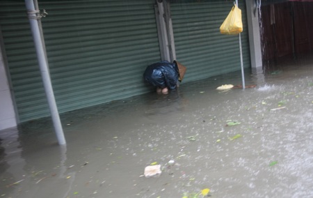 Một hộ dân đóng cửa quan và khóa cửa dưới dòng nước ngập.