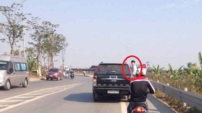 Nam thanh niên đu bên hông ô tô trên suốt quãng đường 10km - 1 Nam thanh niên liều mình bám vào bên hông xe ô tô bán tải đang lao vun vút trên đường (Ảnh cắt từ clip).