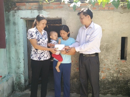 Đại diện chính quyền địa phương trao quà bạn đọc ủng hộ đến gia đình chị Huấn.