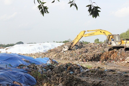Hai người mặc đồng phục bảo vệ đứng canh từ ngoài cổng bãi rác, không cho phóng viên vào tác nghiệp