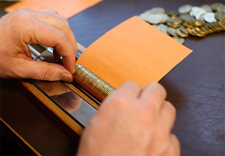 Ông Breiter gói tiền xu Euro vào một tờ giấy.