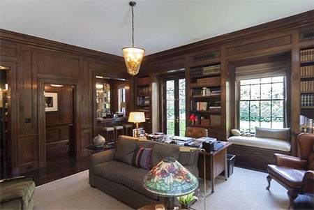 Phòng đọc sách trông rất ấm cúng với tông màu gỗ trầm và những giá sách lớn.