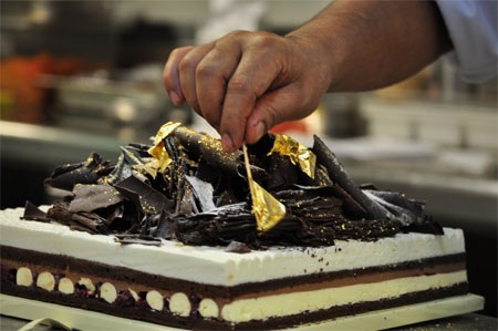 Một đầu bếp trong khách sạn Emirates Palace đang chuẩn bị món bánh ngọt có phủ những lá vàng.