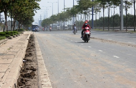  Rãnh thoát nước sát mép đường trên đại lộ Mai Chí Thọ bị bùn, đất bít chặt.