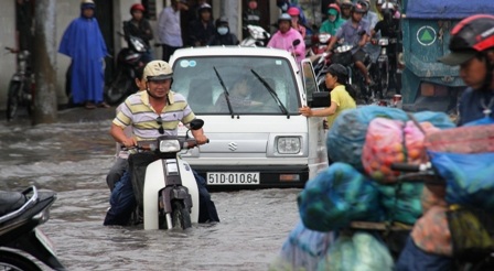 Nhiều người cùng nhau dùng xà beng cạy nắp cống trên đường Phạm Văn Đồng để nước thoát.