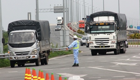 Nhân viên trạm thu phí Long Phước đang hướng dẫn xe tải vào làn để cân tải trọng xe.