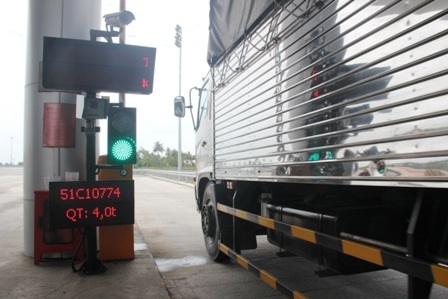 Một chiếc xe chở hàng qua hệ thống cân được biển báo điện tử thông tin quá tải (QT).