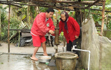 Hạnh phúc vì mấy chục năm mới được... mặc áo trắng - 2 Bà Nuôi cùng con trai bên nguồn nước sạch được dự án “Nước sạch cho cộng đồng” hỗ trợ