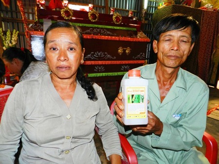 Mẹ không đưa vàng trả nợ chơi game, con tự tử - 1 Vợ chồng ông Nguyễn Văn Tổng bên chai thuốc trừ sâu mà Kiệt dùng để tự tử