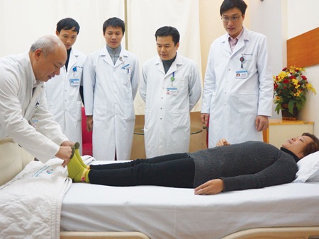 Người đầu tiên thay đĩa đệm nhân tạo tại Việt Nam - 1 Chị Cúc được bác sĩ kiểm tra chức năng vận động khi tái khám sau mổ.