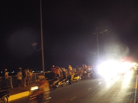 Người đi đường dừng xe theo dõi việc tìm kiếm H. ở dưới cầu, tối 26/4.