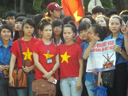 Một nữ sinh với chiếc áo đỏ sao vàng 5 cánh và hình trái tim trên khuôn mặt.