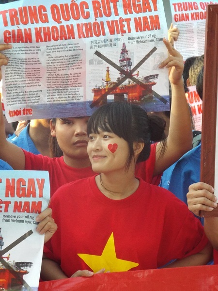 Một nữ sinh với chiếc áo đỏ sao vàng 5 cánh và hình trái tim trên khuôn mặt.