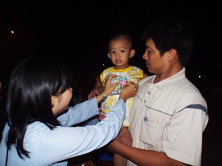 Một em bé đươc cài bông hồng lên ngực.