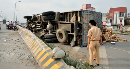 Sau khi đi thằng bằng khoảng 20m trên dải phân cách, chiếc xe tải đổ nghiêng ra đường.