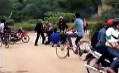 Một Cảnh sát cơ động có động tác như vụt một vật giống gậy vào nam thanh niên áo đen.