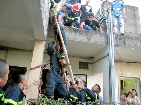 Hà Nội: Giải cứu thiếu nữ ngồi trên mái nhà, thả tiền xuống đất - 1 Phải rất vất vả, lực lượng cứu hộ mới trói được thiếu nữ vào thang tre, đưa xuống đất an toàn.