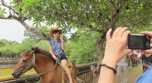 Thích thú ngồi trên lưng ngựa vua chụp hình