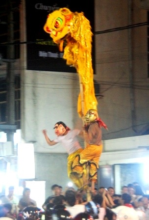 2 ông địa rất quậy leo lên sào giơ tay múa chân đùa giỡn với mọi người làm cả phố cười vang