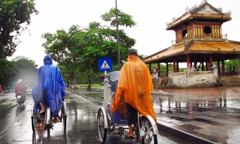 Vất vả đạp xích lô chở khách du lịch thăm thú thành phố trong mưa Huế.