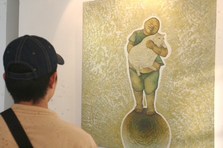 1 SV mỹ thuật đang chăm chú xem tác phẩm của các họa sĩ trẻ