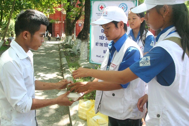 Tình nguyện viên đang phát cơm miễn phí cho 1 thí sinh dân tộc