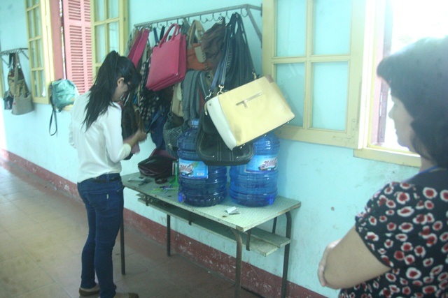 Giám thị đang giám sát 1 thí sinh ra lấy dụng cụ và giấy tờ thi ngoài hành lang