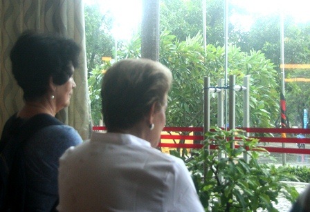 2 nữ du khách Tây lớn tuổi nhìn gió bão qua kính gương tại KS Mường Thanh Huế