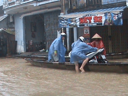 Hàng ngàn ngôi nhà vẫn ngập sâu trong nước lũ - 9 Đưa xe máy lên ghe qua vùng nước sâu.